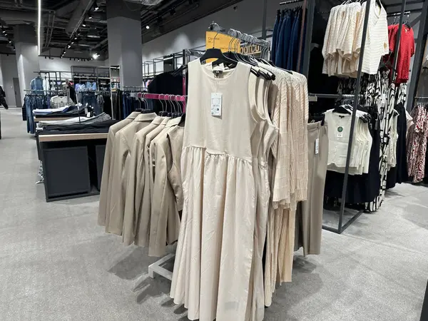 Varşova, Polonya - 28 Nisan 2025: Çağdaş bir perakende mağazasında sergilenen şık bej elbise ve giysi koleksiyonu, geniş bir alışveriş ortamında modern alışverişçiler için moda trendleri ve tarzları vurguluyor