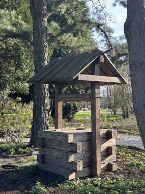 Ağaçların ve yeşilliklerin arasına yerleşmiş, eğimli bir çatısı olan ahşap kuyu, doğal malzemeler ve işçiliği ön plana çıkarıyor, güzel bir bahçe ortamında sakin bir atmosfer yaratıyor.