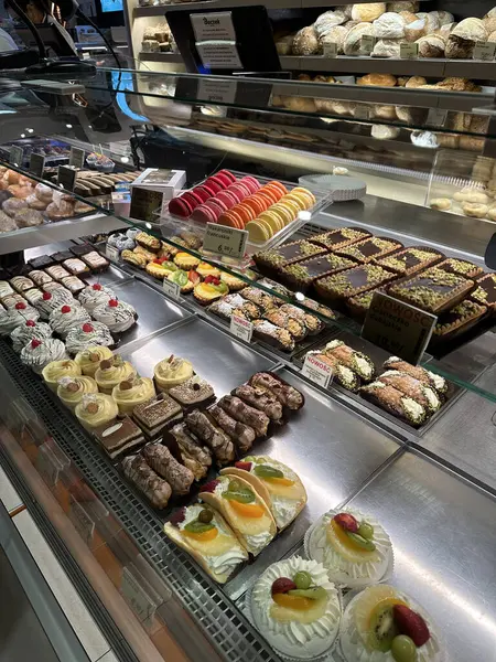 Fırında sergilenen çeşitli hamur işleri ve tatlılar, canlı renkler, karmaşık tasarımlar ve cazip tatlı çeşitleri.