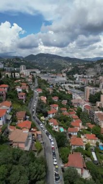 Düşük katlı binalar, yeşil ağaçlar ve dolambaçlı bir yol olan yerleşim alanının havadan görüntüsü. Gökyüzü birkaç bulutla açık, güneşli bir günü işaret ediyor. Turizm pazarlaması için, Sosyal medya içeriği