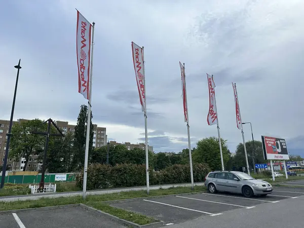 Varşova, Polonya - 22 Mayıs 2025: Marka bayrakları ticari bir alanın dışındaki rüzgarda dalgalanıyor, parlak renkleriyle kentsel çevreyi güçlendiriyor