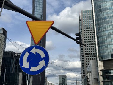 Varşova, Polonya - 22 Mayıs 2025: Çevresel trafik tabelası arka planda kentsel çevre ve şehir dinamiklerini gösteren modern binalarla belirgin bir şekilde duruyor