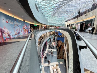 Varşova, Polonya - 22 Mayıs 2025: Çağdaş alışveriş merkezi benzersiz kıvrımlı tasarım, renkli reklamlar ve perakende deneyimlerinin keyfini çıkaran çeşitli müşteriler barındırıyor