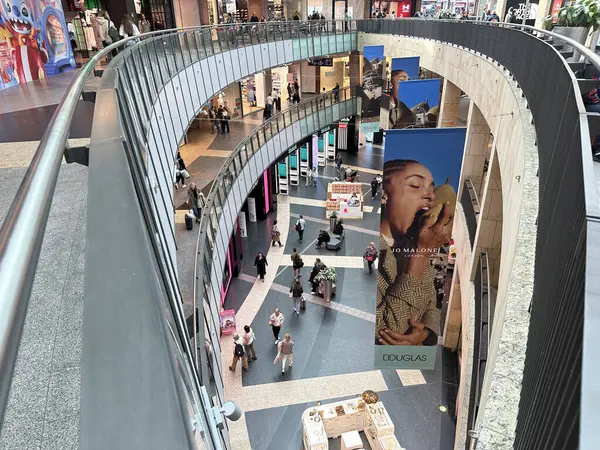 Varşova, Polonya - 22 Mayıs 2025: Kıvrımlı tasarımlı, renkli reklamları olan ve çeşitli mağazaları keşfeden, dinamik bir atmosfer yaratan çağdaş alışveriş merkezinin içi