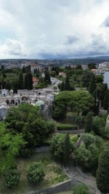 Birden fazla bina ve yeşil alanlar olan modern yerleşim alanının havadan görüntüsü. Sahne, bulutlu bir gökyüzünün altında alçak ve yüksek katlı dairelerin karışımını içeriyor..