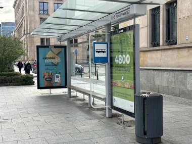 Varşova, Polonya - 22 Mayıs 2025: Novy Swiat 02 'de bulunan otobüs durağı, canlı kent ortamında reklamlar ve açık bir otobüs tabelası sergiliyor