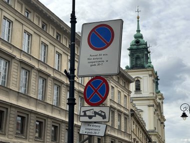 Varşova, Polonya - 22 Mayıs 2025: Şehir merkezinde park kurallarının olmadığı, tarihi binaların ve şehir manzarasını geliştiren bir kilise kulesinin yer aldığı sokak tabelaları