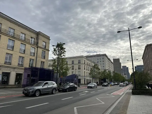 Varşova, Polonya - 22 Mayıs 2025: Kentsel sokak manzarası otomobilleri yol, modern binalar ve şehir atmosferini artıran çarpıcı bulutlu bir gökyüzü içeriyor