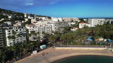 Gök mavisi Riviera kıyı şeridi ve Fransa 'nın Cannes şehrinin havadan görünüşü. Modern binalar ve palmiye ağaçları açık mavi gökyüzüne karşı görülebilir. Seyahat videoları, turizm tanıtımları, belgeseller