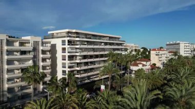 Gök mavisi Riviera kıyı şeridi ve Fransa 'nın Cannes şehrinin havadan görünüşü. Modern binalar ve palmiye ağaçları açık mavi gökyüzüne karşı görülebilir. Seyahat videoları, turizm tanıtımları, belgeseller