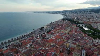 Kıyı şehri, uzun sahil manzarası ve şehir manzarası. Ufuk çizgisinde binalar ve kıyı boyunca dolambaçlı bir yol yer alıyor. Kültürel belgeseller, seyahat ve turizm, tarihi mimari