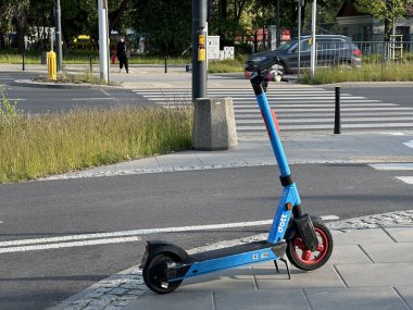 Varşova, Polonya - 22 Mayıs 2025: Elektrik scooter 'ı yaya geçidinin yanındaki kaldırıma park edilmiş, kentsel hareketlilik ve şehir manzarasındaki modern ulaşım seçeneklerini vurguluyor