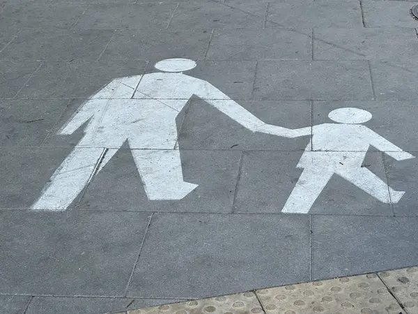 Varşova, Polonya - 22 Mayıs 2025: Yaya geçidi grafikleri yetişkin ve çocuğun kaldırımda el ele tutuşup şehir ortamında güvenliği ve aileyi ön plana çıkardığını gösteriyor