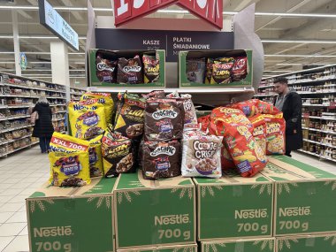 Varşova, Polonya - 22 Mayıs 2025: Nestle mısır gevreği ürünleri, canlı paketleme ve çeşitliliğe sahip müşterileri çeken bir market koridorunda belirgin bir şekilde sergilenmektedir