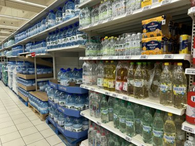 Varşova, Polonya - 22 Mayıs 2025: Süpermarket koridoru çeşitli su markaları ve boyutlarıyla dolu, raflarda müşterilerin seçebileceği düzgünce düzenlenmiş