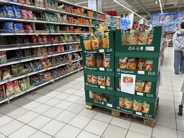 Varşova, Polonya - 22 Mayıs 2025: Market koridorundaki abur cubur sergisi raflarda renklendirici cips ve abur cuburlar sergilenerek davetkar bir alışveriş ortamı yaratıyor.