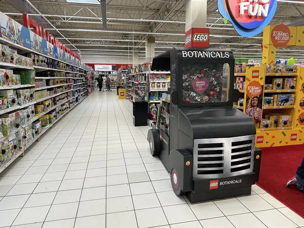 Varşova, Polonya - 22 Mayıs 2025: LEGO Botanik kamyonları renkli ürünler ve alışveriş yapan müşterilerle dolu canlı bir oyuncak mağazası koridorunda duruyor