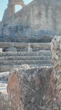 Yıpranmış taş basamaklar, tarihi ve arkeolojik güzelliği vurgulayarak, berrak mavi gökyüzüne karşı anıtsal yapıyı vurguluyor.