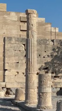 Yıpranmış taş kalıntıları belirgin bir sütun ve dokulu duvarlar, antik mimariyi ve sakin bir açık hava ortamındaki tarihi kalıntıların güzelliğini vurguluyor.