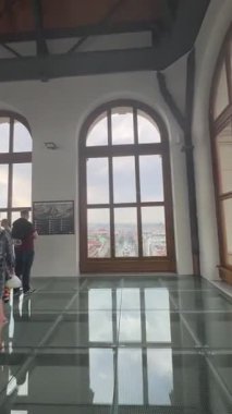 Prag, Çek Cumhuriyeti - 22 Nisan 2023: Geniş ahşap pencere, bulutlu bir gökyüzü altında ağaçlarla kaplı caddeleri, araçları ve binaları gözler önüne sererek sakin bir şehir ortamını çağrıştırıyor.