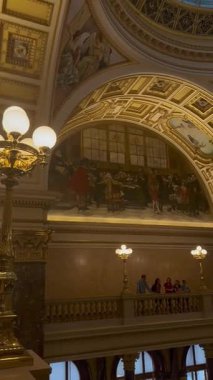 Prag, Çek Cumhuriyeti - 22 Nisan 2023: Altın aksanlı ve cam kubbeli mimari tavan, duvar resimleri ve aydınlatmalarla süslenmiş, tarihi bir iç mekanda zarif bir atmosfer yaratıyor.