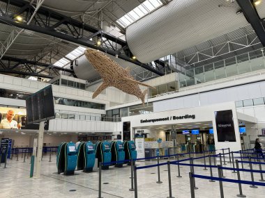 Nice, Fransa - 10 Mayıs 2025: Büyük ahşap balık heykeli havaalanı terminalinde asılı, kontrol gişeleri ve dijital ekranlarla modern tasarımı vurguluyor