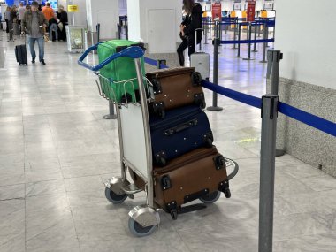 Nice, Fransa - 10 Mayıs 2025: Canlı bavullarla dolu bavul havaalanı terminaline yerleştirildi, seyahat gereksinimlerini ve hareketli çevreyi vurguladı