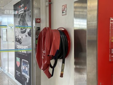 Nice, Fransa - 10 Mayıs 2025: İtfaiye hortumu güvenlik ekipmanlarını ve kamu alanındaki acil durum hazırlıklarını vurgulayarak güvenli bir şekilde duvara monte edilmiştir.