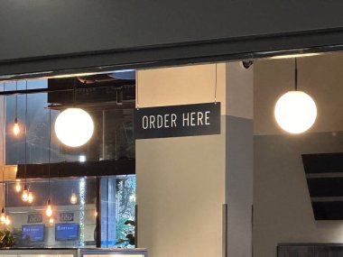 Nice, Fransa - 10 Mayıs 2025: Çağdaş Cafe Space gösterileri Bir Sipariş Burada zarif ışıklandırma ile imzalayın, müşteriler için bir karşılama ortamı oluşturun