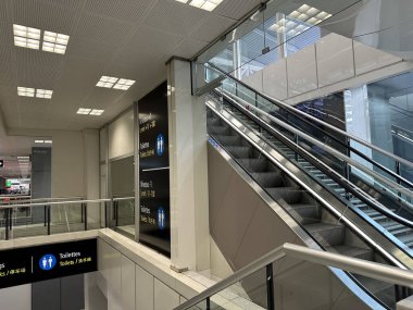 Nice, Fransa - 10 Mayıs 2025: Yürüyen merdivenler ve açık işaret ile çağdaş havaalanı çevresi, gezginler ve ziyaretçiler için hoş bir atmosfer sağlıyor