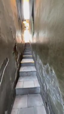 Prag, Çek Cumhuriyeti - 23 Nisan 2023: Kıvrımlı duvarları olan dar merdivenler, sonunda parlak güneş ışığına çıkıyor ve davetkar bir ortam yaratıyor.