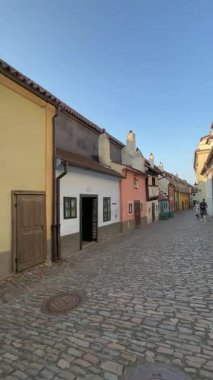 Prag, Çek Cumhuriyeti - 23 Nisan 2023: Renkli binalarla tarihi bölgede kaldırım taşı patikası, resimde gezinen bir erkek ve kadın