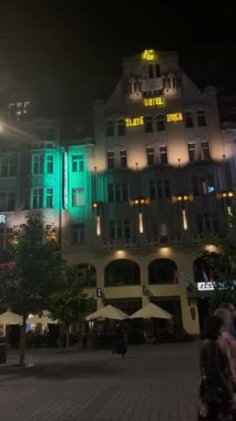 Prag, Çek Cumhuriyeti - 23 Nisan 2023: Gece kalabalık cadde Otel Büyükelçisi ve restoran tabelalarının önünden geçen yayalar canlı şehir yaşamını yakalıyor