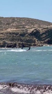 Rodos, Yunanistan - 17 Ağustos 2023: Okyanus dalgaları üzerinde süzülen jet ski açık gökyüzünde süzülen renkli uçurtmalarla yaz eğlencesi ve macera sergiliyor