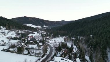 Karla kaplanmış manzaralı kış köyü, tuhaf evler ve dolambaçlı yollar, görkemli dağlara karşı kurulmuş ve yemyeşil ağaçlar, huzurlu bir atmosfer yaratıyor.
