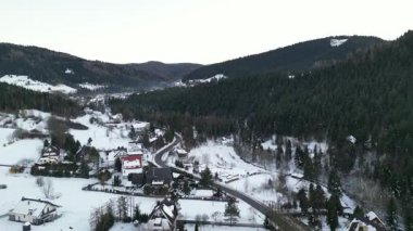 Karla kaplı evleri ve etrafını saran sarmal yolları olan manzaralı kış manzarası güzel doğal bir ortamda huzurlu bir atmosfer yaratıyor.