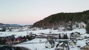 Güzel kış manzaraları, karla kaplı tepeler ve vadideki tuhaf evler, dolambaçlı bir yol, huzur dolu manzaraya derinlik katıyor.