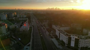 Hava perspektifi, gün batımında hareketli bir şehir manzarası yakalar. Yoğun bir yol, yerleşim yerleri ve bir kilise, hareketli bir şehir atmosferi yaratır.