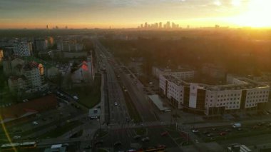 Günbatımında canlı bir şehir manzarasının hava perspektifi, ufuk çizgisini, yollardaki trafiği ve çağdaş binaları vurguluyor, kentsel enerji ve dinamik ortamı yansıtıyor