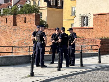 Varşova, Polonya - 13 Haziran 2025: Altı üniformalı polis memuru, tarihi tuğla duvarın yanındaki sokakta tartışmalara girdi.