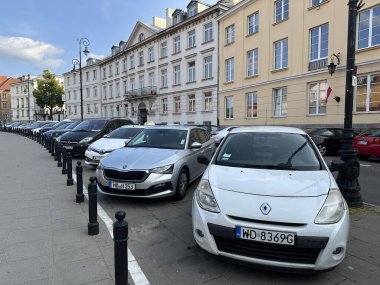 Varşova, Polonya - 13 Haziran 2025: Polonya 'da bir şehir caddesine park edilmiş arabalar, arka planda çeşitli modeller ve klasik mimarinin yer aldığı