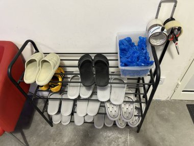 Varşova, Polonya - 01 Temmuz 2025: Ayakkabı askısı, üzerinde mavi plastik poşetler ve bant bulunan çeşitli siyah beyaz terlikler barındırıyor.