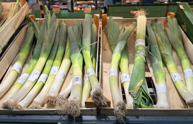 Marketteki ahşap kasalarda sergilenen canlı yeşil pırasalar, tazeliği ve kaliteyi vurguluyor, aşçılık ve sağlıklı yemek hazırlıkları için mükemmel.