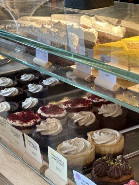 Bolonya, İtalya - 10 Temmuz 2025: Fırın vitrininde çeşitli gurme kekler ve kekler, zengin dokular ve tatlı meraklılarına cazip renkler sunuluyor