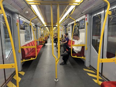 Varşova, Polonya - 29 Ağustos 2025: Sarı tırabzanlar ve kırmızı koltukların yer aldığı boş metro treninin içi