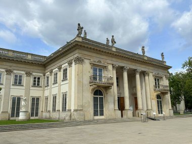 Klasik tasarım elementlerine sahip büyük tarihi yapı, uzun sütunlar ve karmaşık heykeller, verimli bir avlu ve açık gökyüzü ile çevrili, mimari güzelliği somutlaştıran