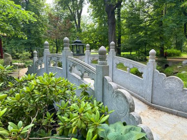 Canlı yapraklar ve ağaçlar arasında yuva yapmış güzel taş köprüler ziyaretçileri sakin bahçeyi keşfetmeye davet ediyor.