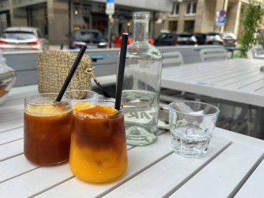 Zarif bardaklarda buzlu içecekler. Çağdaş bir açık masa üzerinde pipetler. Canlı renkler ve ılık hava koşulları için mükemmel bir ortam.