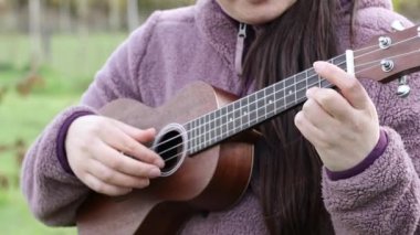 Çimlerin üzerinde ukelele çalan tanınmamış bir kadın. Yüksek kalite fotoğraf
