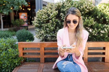 Akıllı telefon kullanan gülümseyen genç bir kadın. İnternet ve sosyal medya bağımlılığı. Yüksek kalite fotoğraf